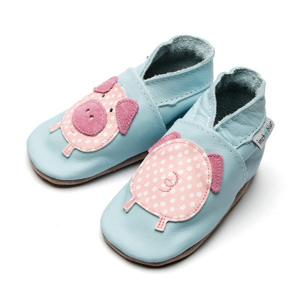 A pair of inch blue barefoot walking baby shoes. Soft leather shoes with an applique pig design